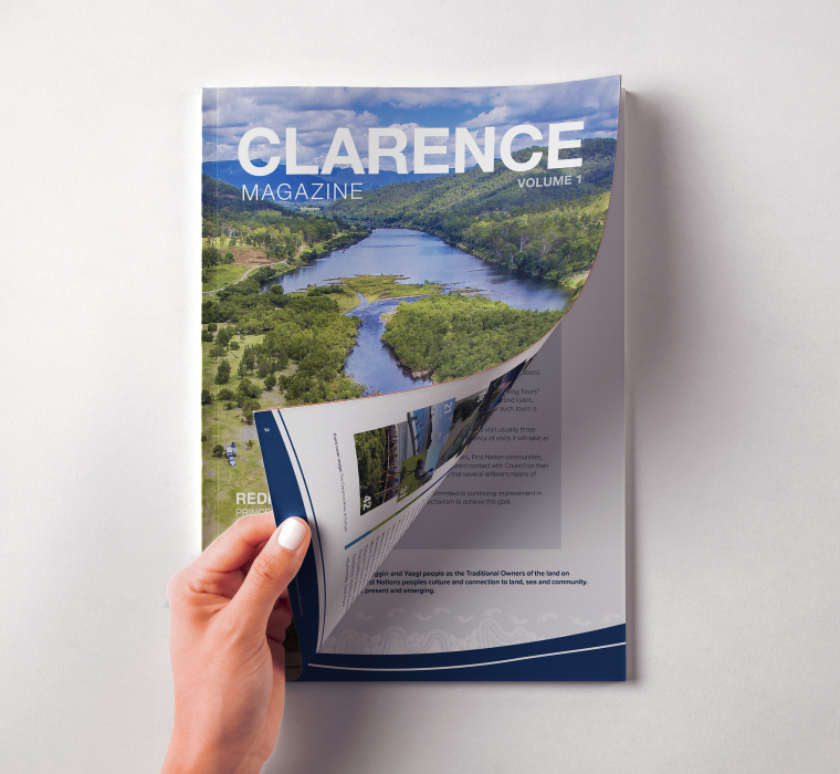 Image of Clarence Magazine cover. Front page being turned by a hand.