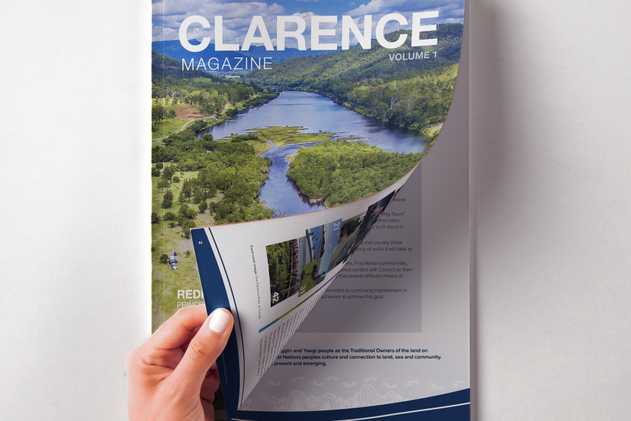 Image of Clarence Magazine cover. Front page being turned by a hand.